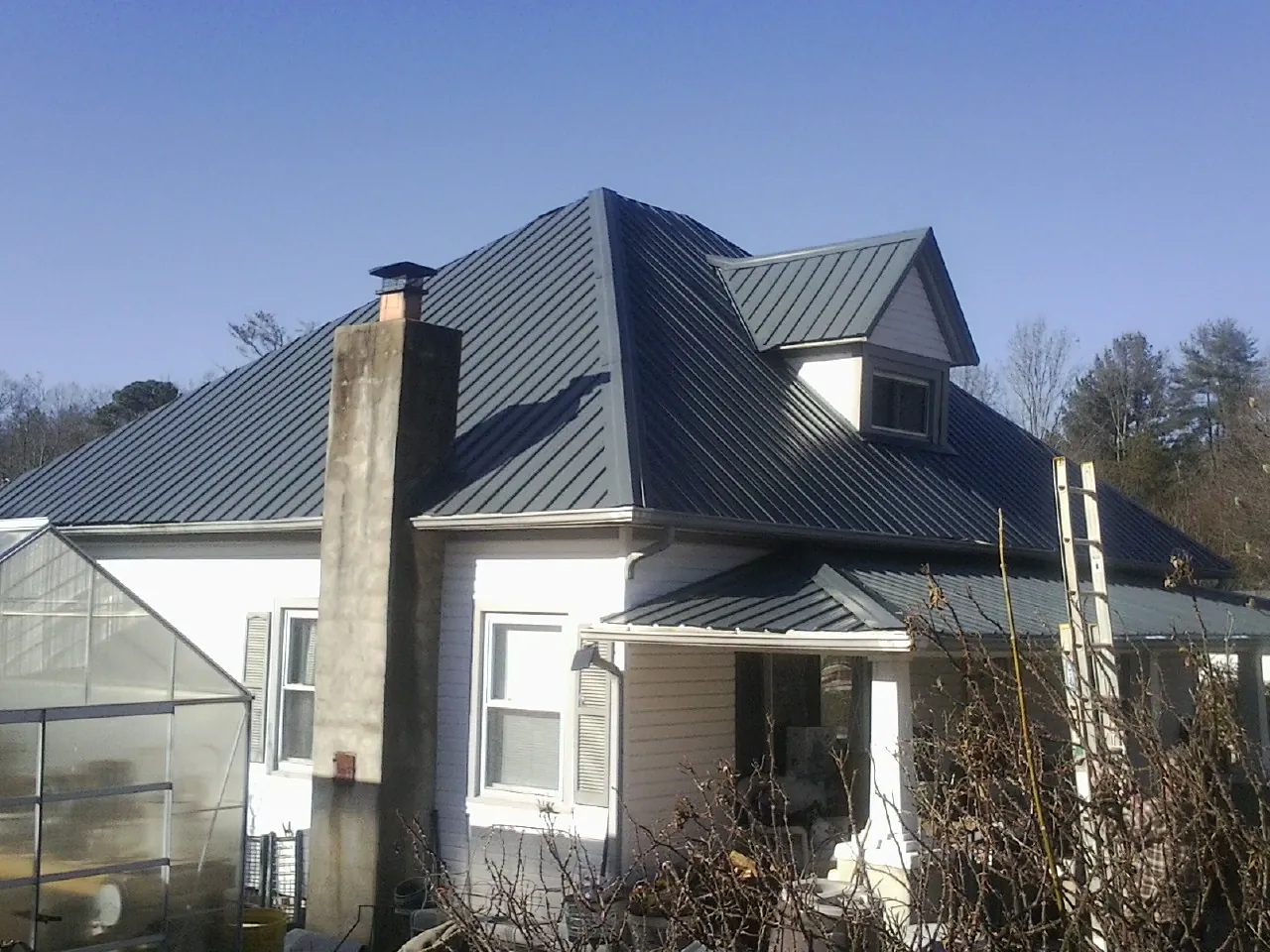 Dark blue standing seam metal roof on a white farmhouse with dormer — Slate & Tile Roof Repair by Roofing Brothers in Doon