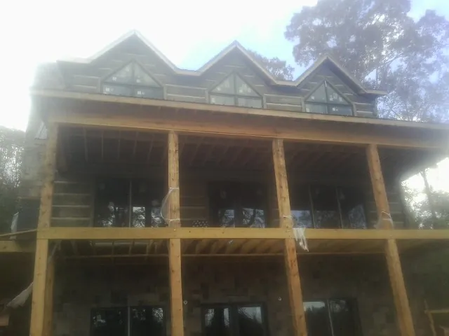 Dormers and porch framing on a large log home under construction — Roof Coating work by our crew in Doon