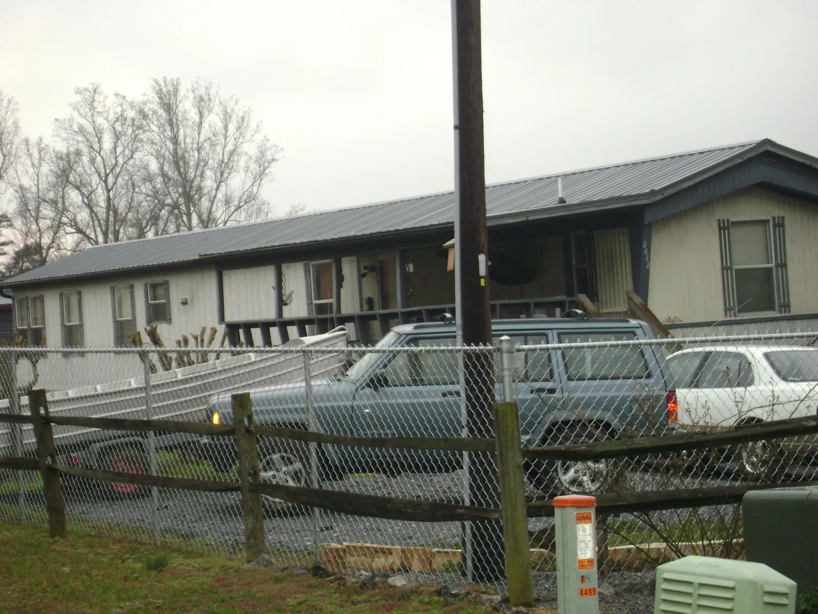 Dark metal roof on a long single story building behind a chain link fence in Doon