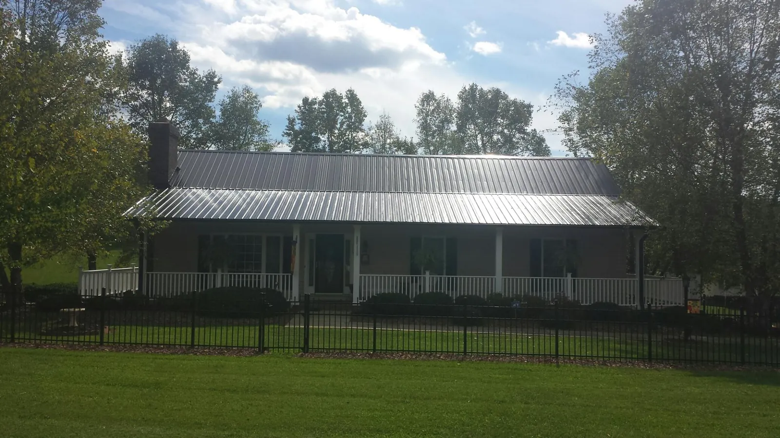 Gray metal roof on a brick ranch with a full width front porch — Gutter Guard Installation work by our crew in Doon